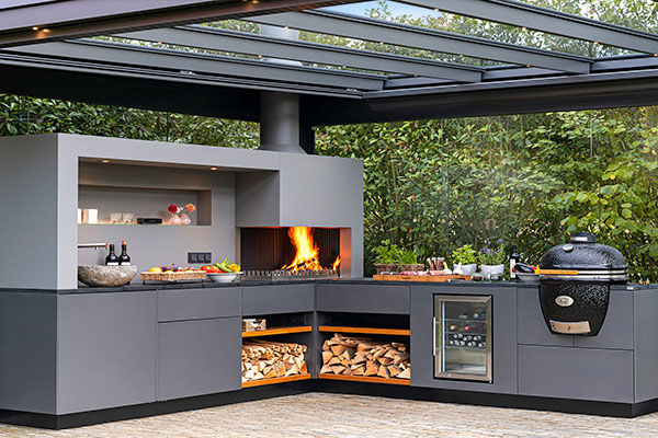 Cuisine d'été sous une pergola équipée de rideaux de verre de jour